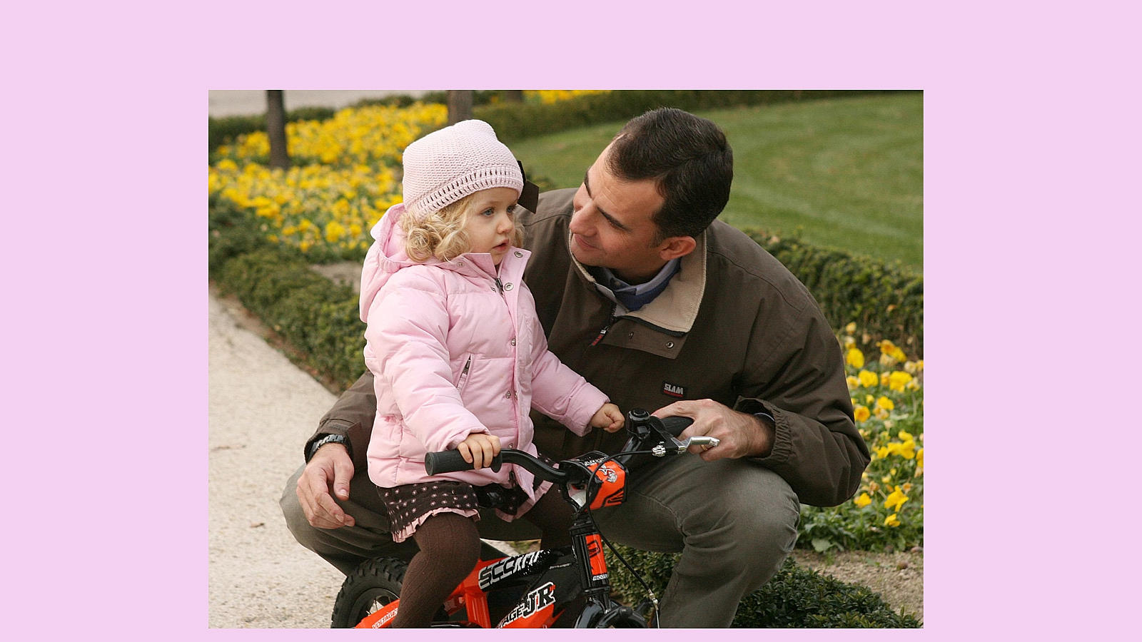 La Princesa, con un gorrito rosa a juego con su abrigo y su vestido, aprende a montar en bici en los jardines del Palacio de la Zarzuela junto a su padre Don Felipe