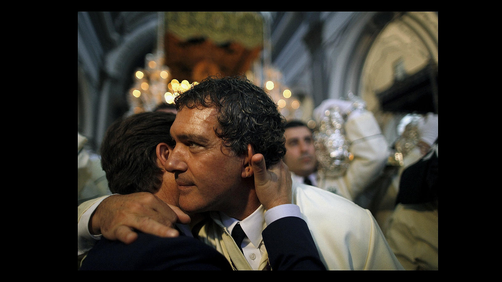 Antonio Banderas se abraza con uno de los compañeros de su hermandad antes de que se inicie la procesión de las  