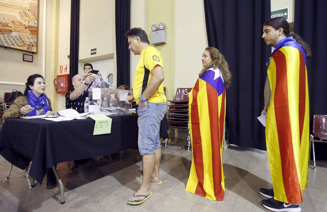 Ciudadanos portando banderas independendistas, esperan su turno para votar en el Casinet de Hostafrancs de Barcelona