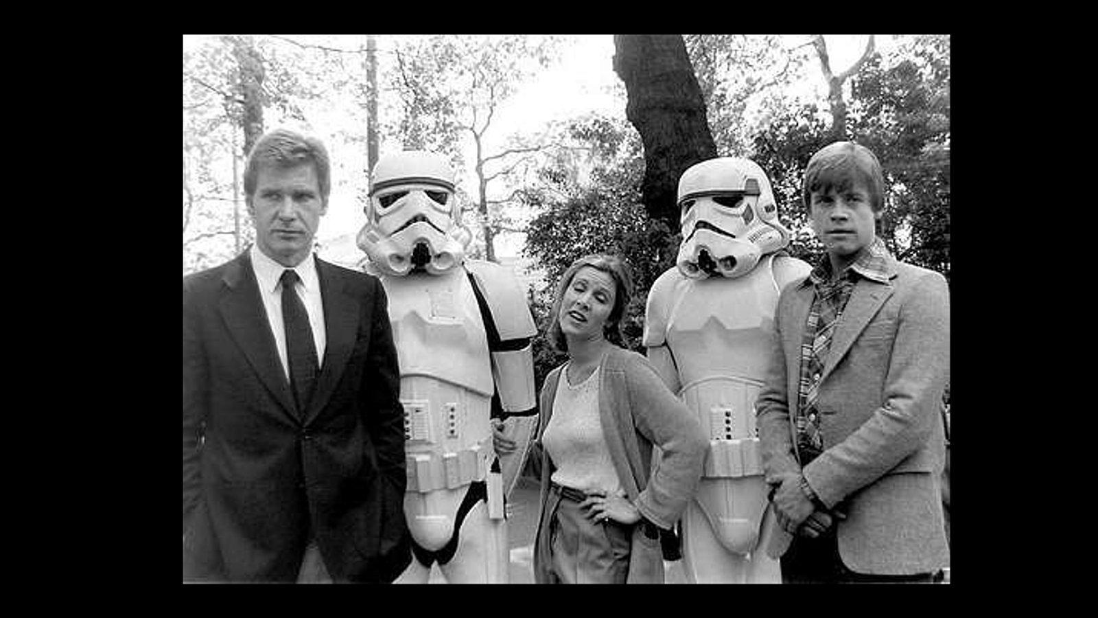 Harrison Ford (izquierda), Carrie Fisher y Mark Hamill, posando después del rodaje con dos soldado imperiales  