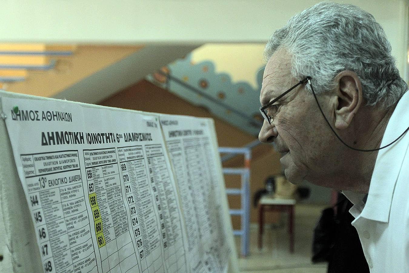 Un griego revisa la lista para saber cuál es la mesa en la que debe votar este domingo, durante el referéndum griego